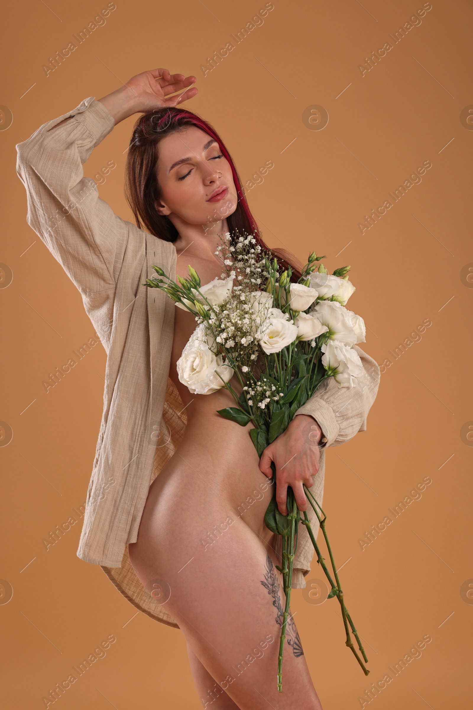 Photo of Sexy nude woman with bouquet of flowers and shirt on beige background