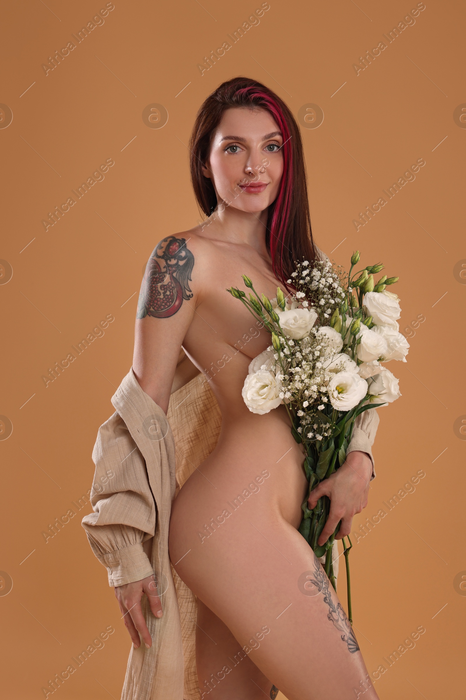 Photo of Sexy nude woman with bouquet of flowers and shirt on beige background