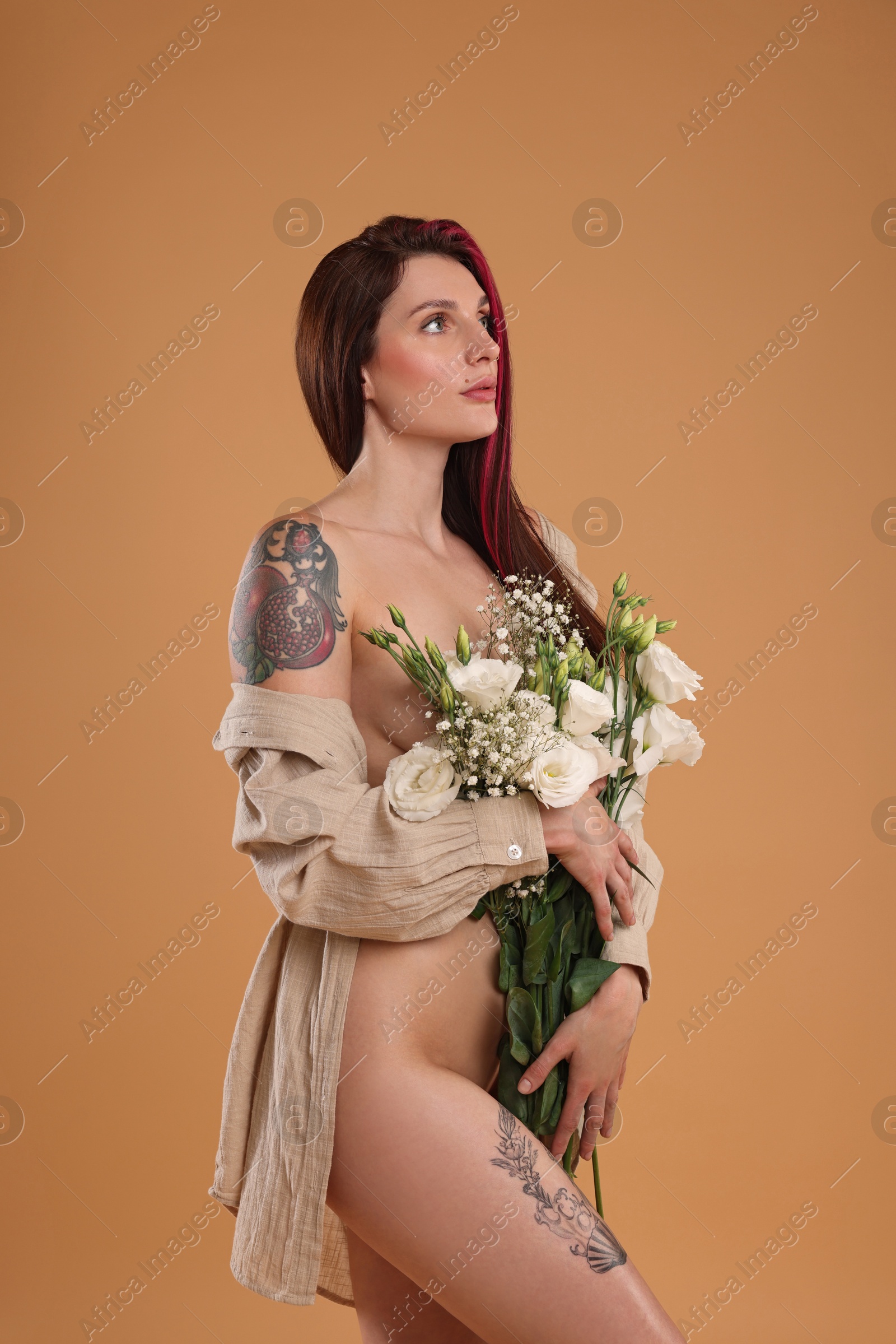 Photo of Sexy nude woman with bouquet of flowers and shirt on beige background