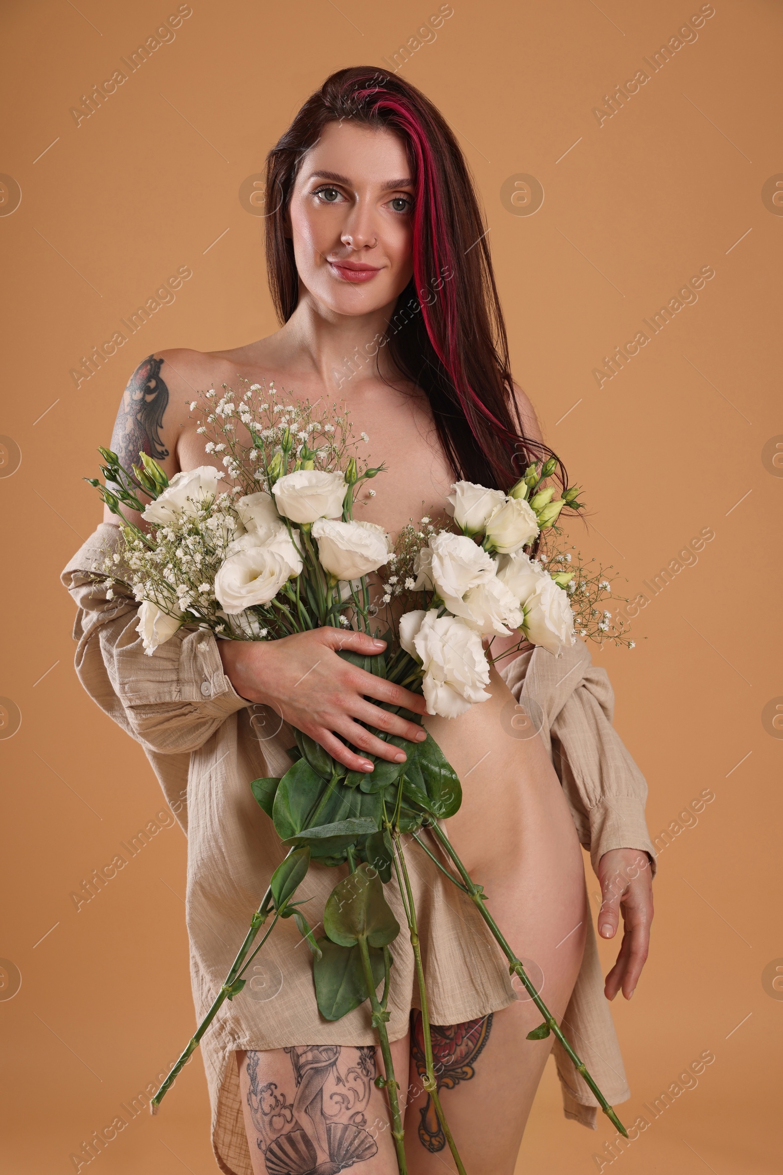 Photo of Sexy nude woman with bouquet of flowers and shirt on beige background