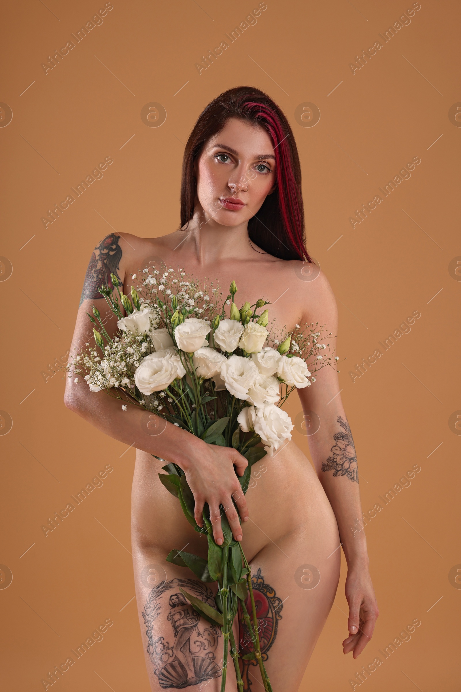 Photo of Sexy nude woman with bouquet of flowers on beige background