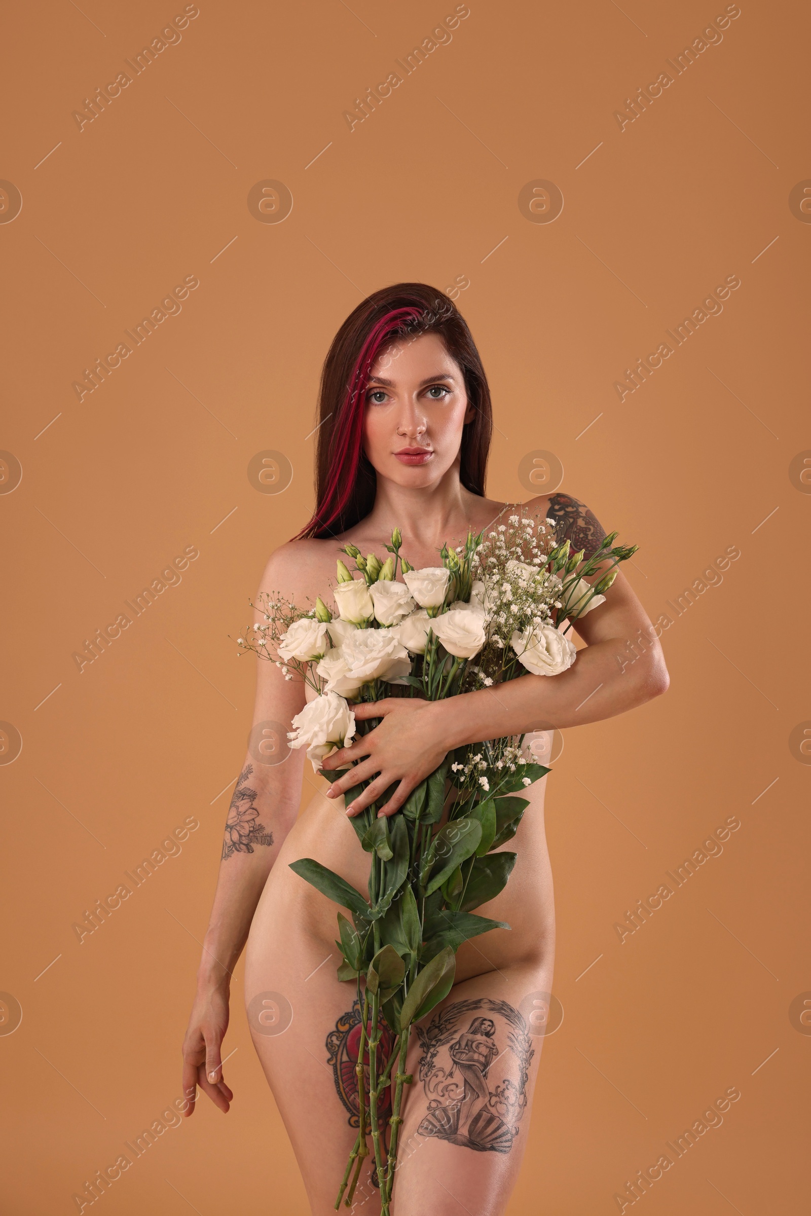 Photo of Sexy nude woman with bouquet of flowers on beige background