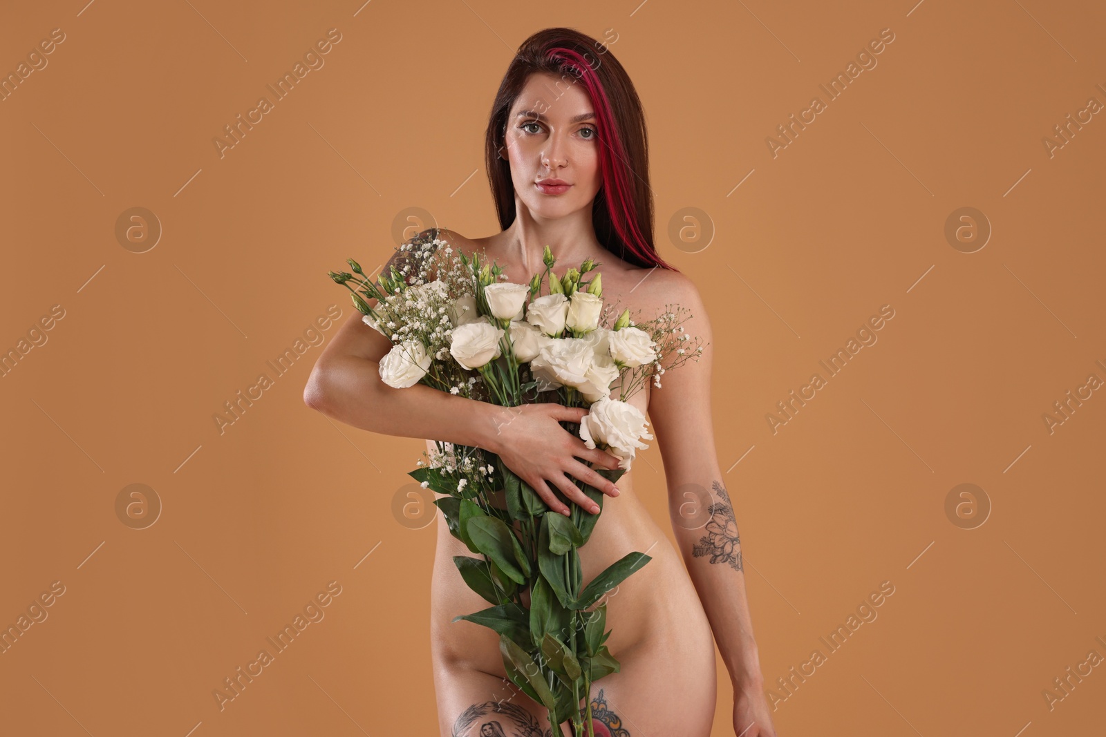 Photo of Sexy nude woman with bouquet of flowers on beige background