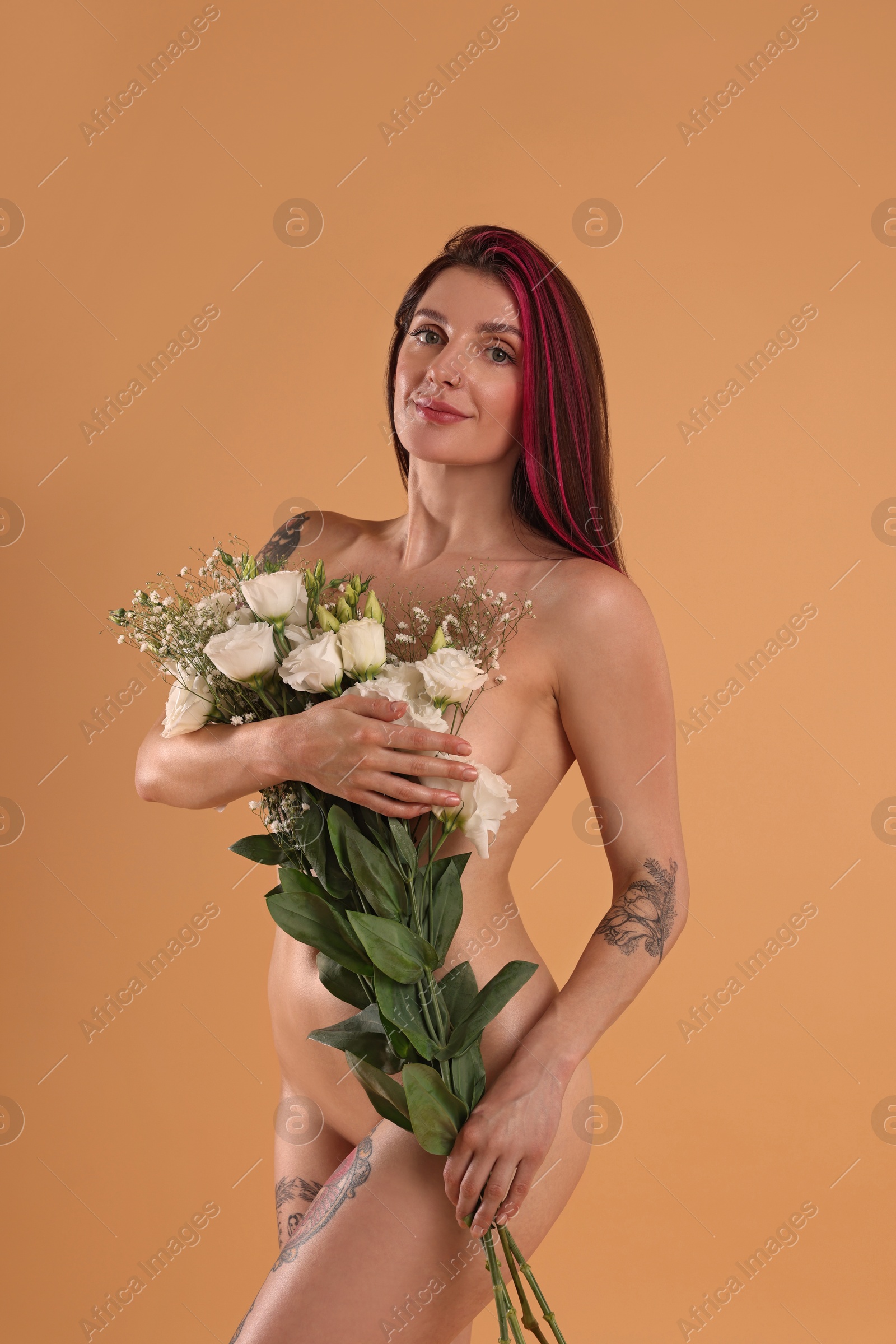 Photo of Sexy nude woman with bouquet of flowers on beige background