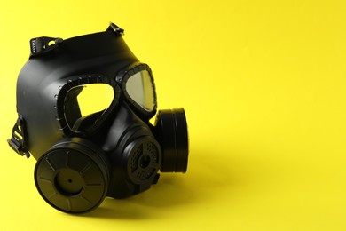 Photo of One gas mask on yellow background, space for text. Safety equipment