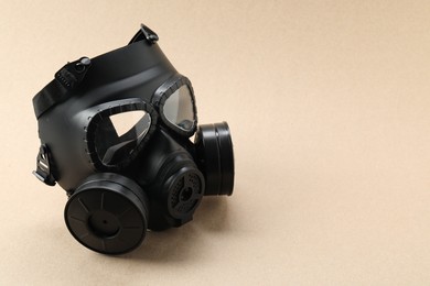 Photo of One gas mask on beige background, space for text. Safety equipment