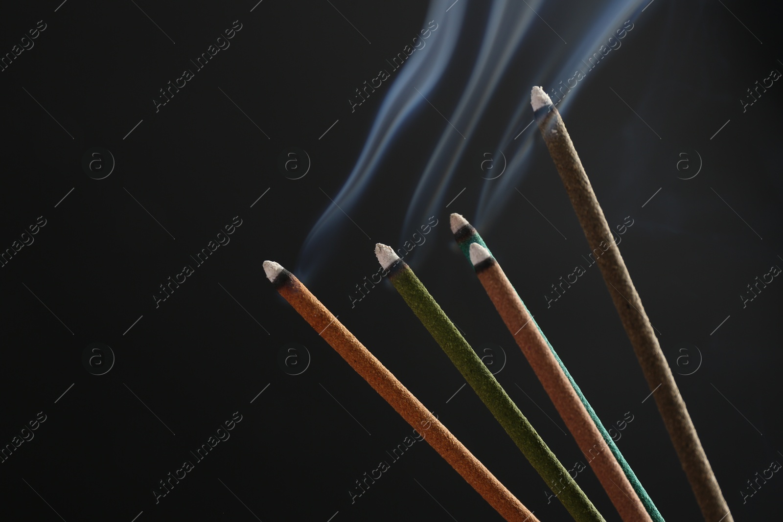 Photo of Aromatic incense sticks smoldering on black background