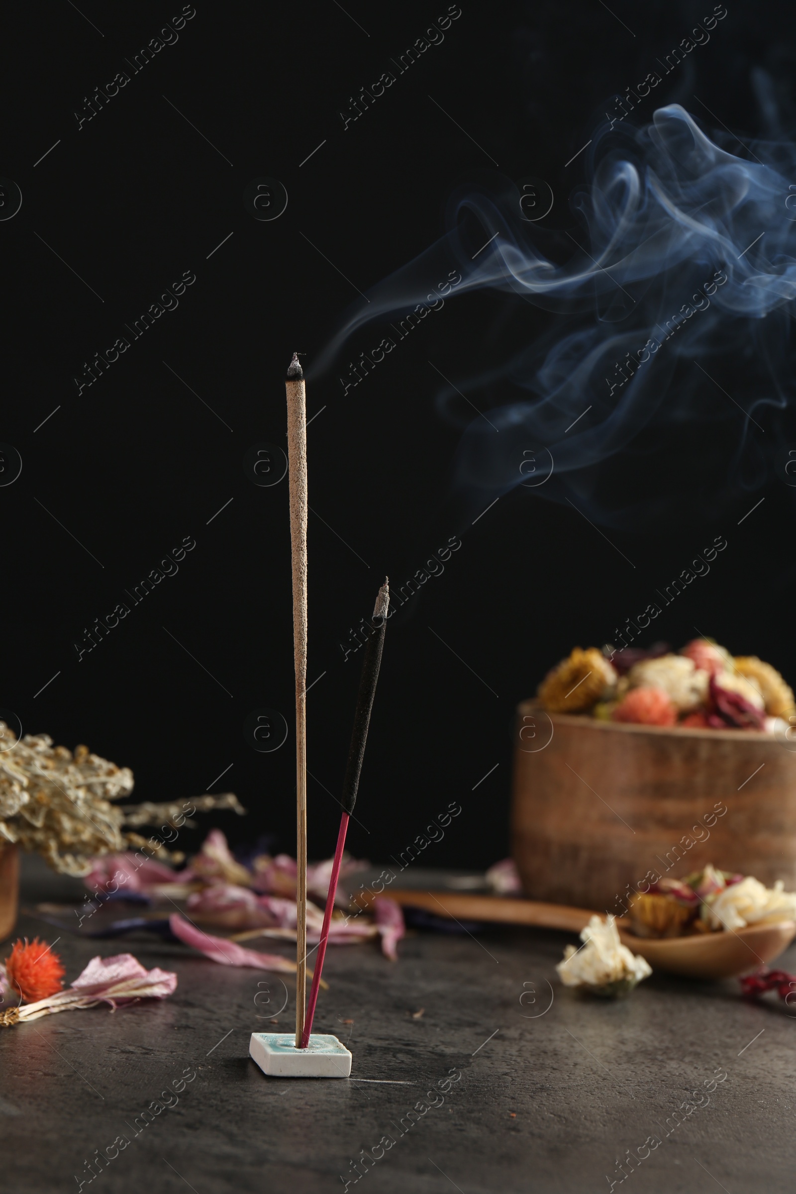 Photo of Aromatic incense sticks smoldering on grey table