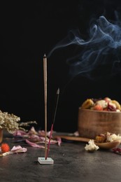 Photo of Aromatic incense sticks smoldering on grey table