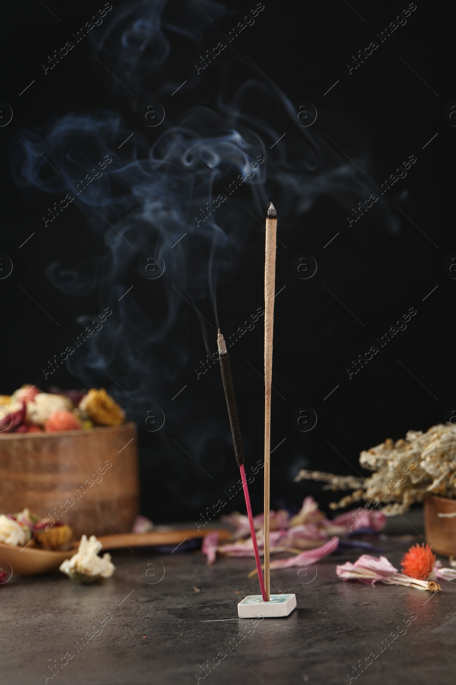 Photo of Aromatic incense sticks smoldering on grey table