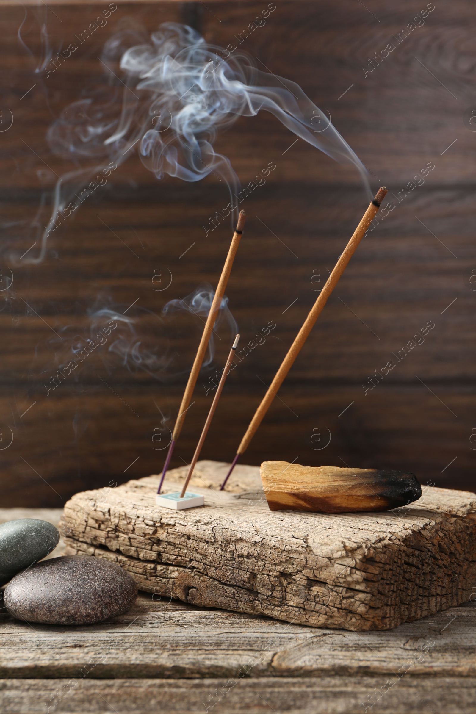 Photo of Aromatic incense sticks smoldering on wooden table