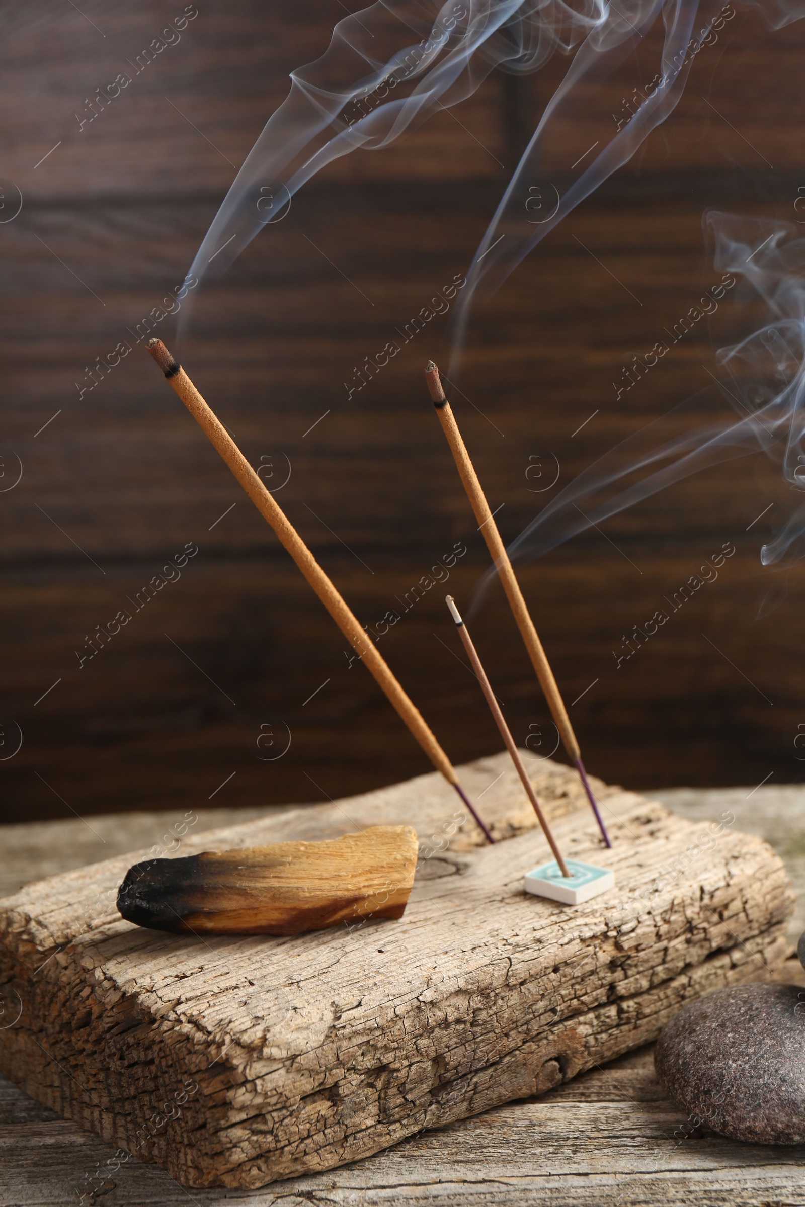 Photo of Aromatic incense sticks smoldering on wooden table