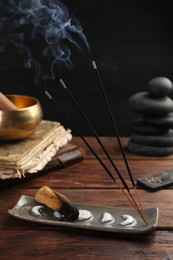 Photo of Aromatic incense sticks smoldering on wooden table