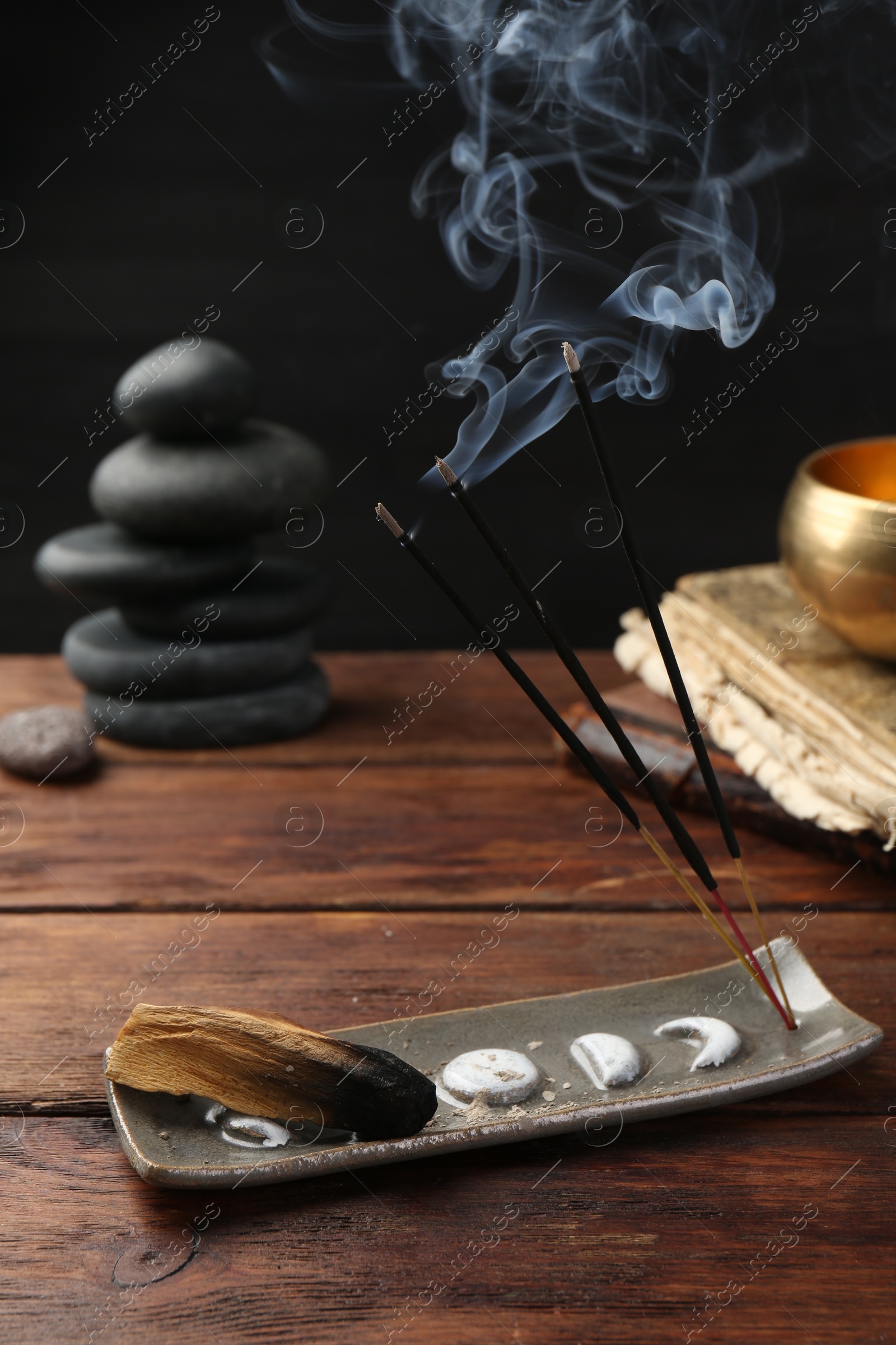 Photo of Aromatic incense sticks smoldering on wooden table