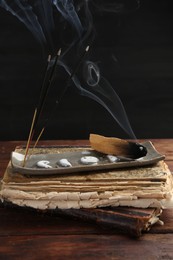 Photo of Aromatic incense sticks smoldering on wooden table