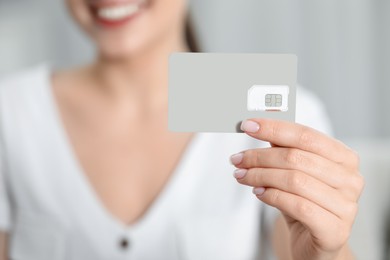 Photo of Woman holding SIM card indoors, closeup view