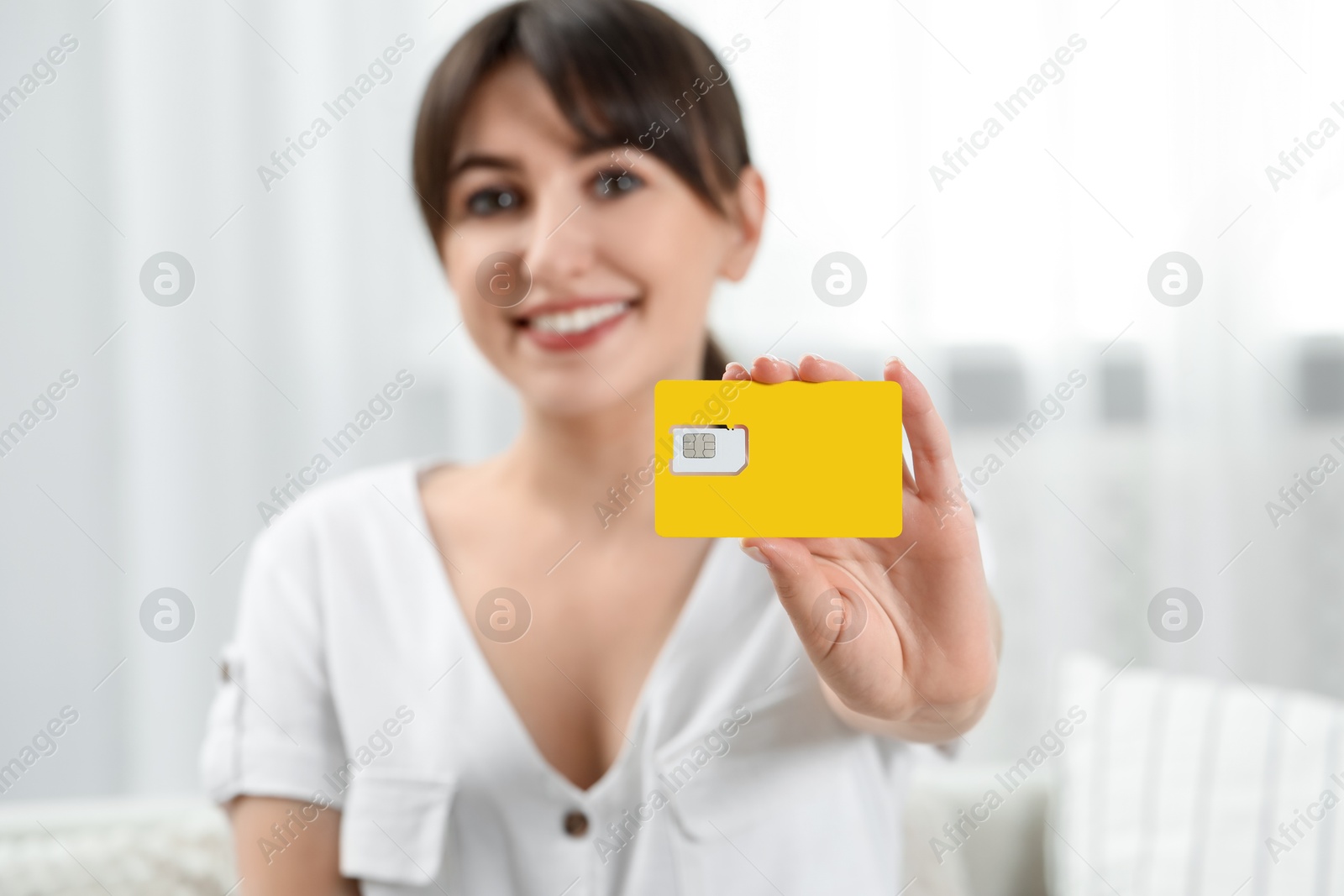 Photo of Woman holding SIM card at home, selective focus