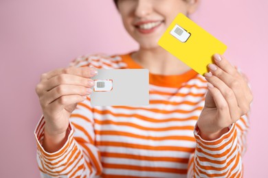 Photo of Woman holding SIM cards on pink background, closeup