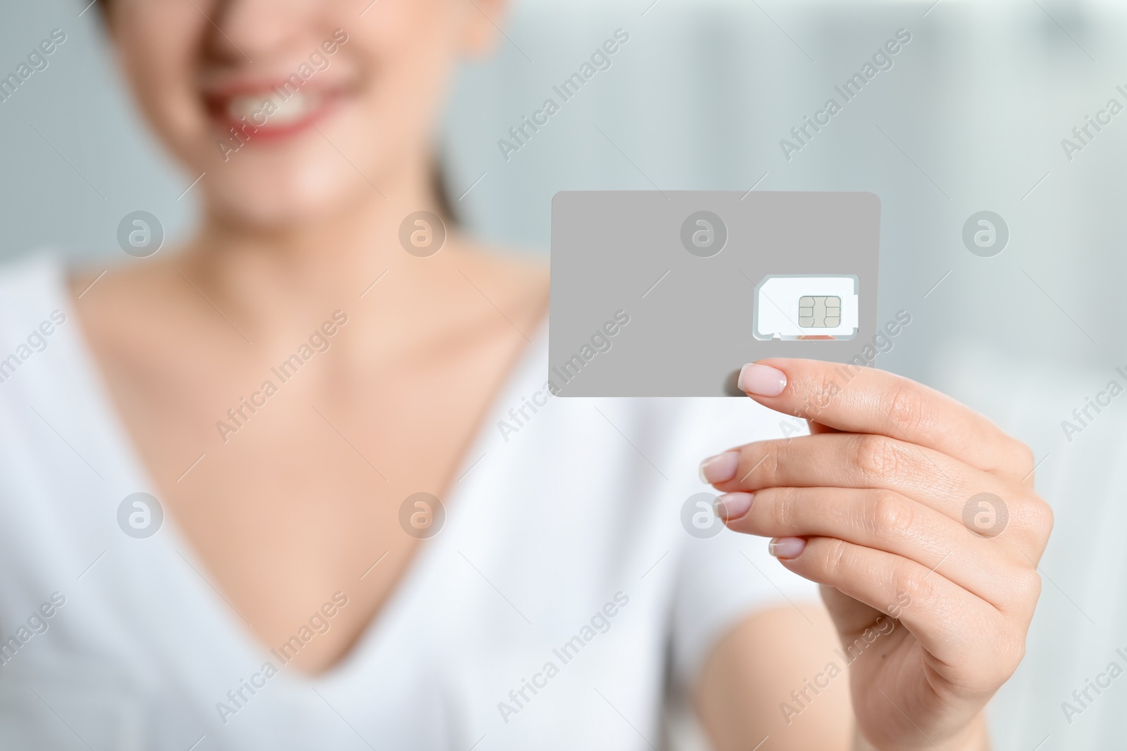 Photo of Woman holding SIM card at home, closeup