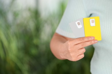 Photo of Woman holding SIM cards on blurred background, closeup. Space for text