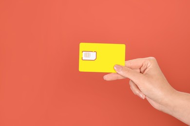 Photo of Woman holding SIM card on terracotta background, closeup. Space for text