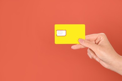 Photo of Woman holding SIM card on terracotta background, closeup. Space for text