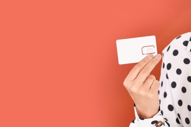 Photo of Woman holding SIM card on terracotta background, closeup. Space for text