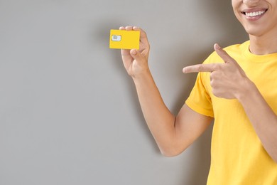 Photo of Man holding SIM card on grey background, closeup. Space for text