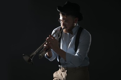 Professional musician playing trumpet on black background