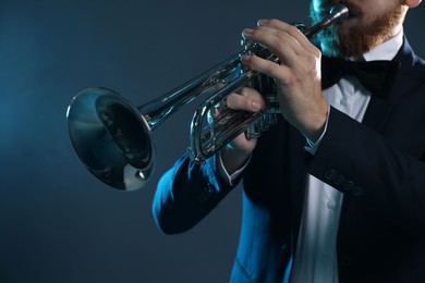 Photo of Professional musician playing trumpet on dark background, closeup