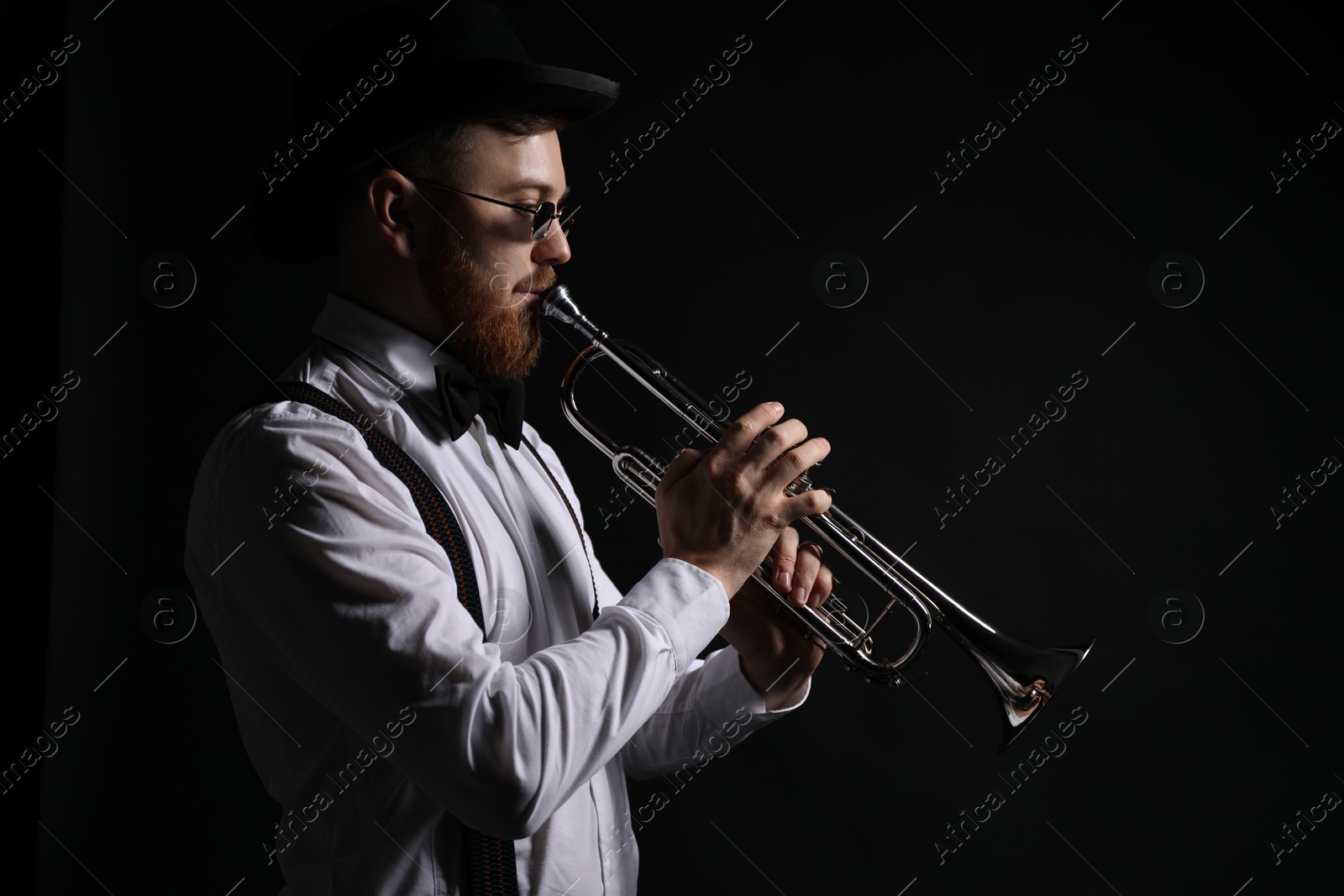 Photo of Professional musician playing trumpet on black background