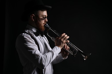 Professional musician playing trumpet on black background