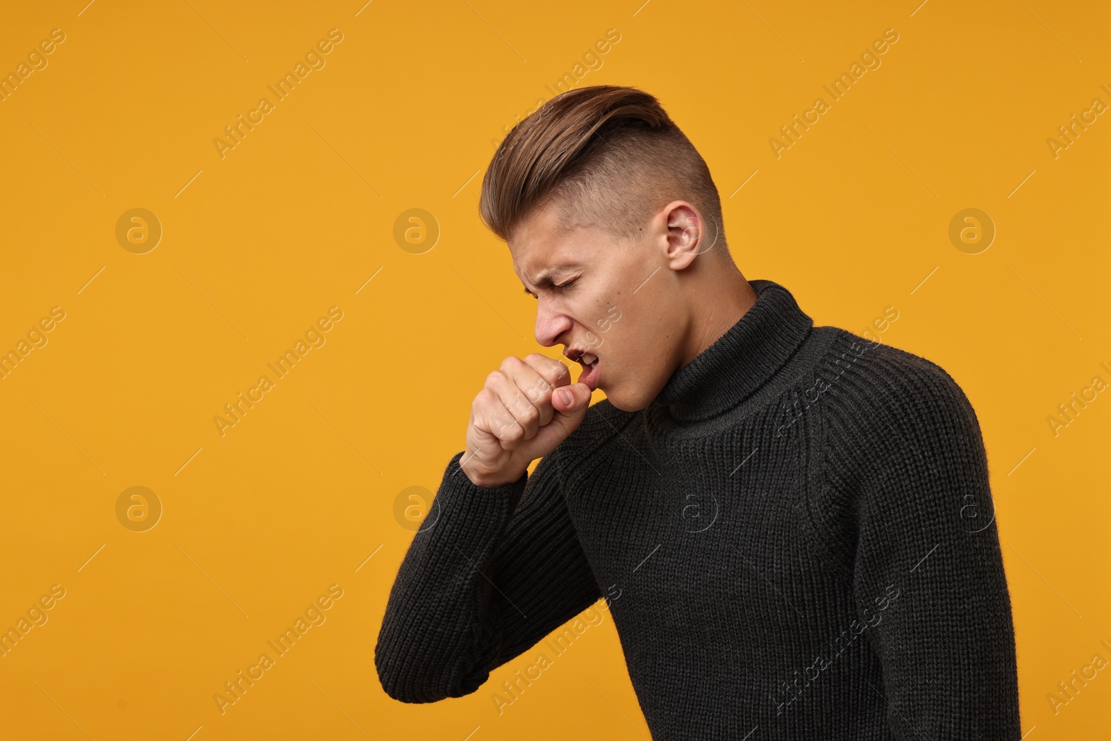 Photo of Sick man coughing on orange background, space for text. Cold symptoms