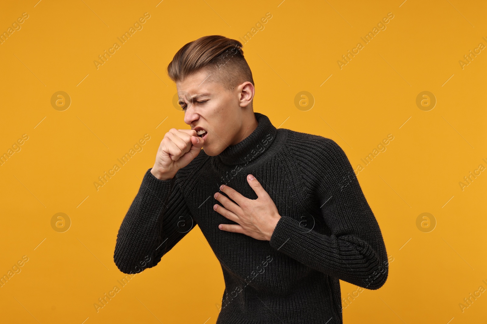 Photo of Sick man coughing on orange background. Cold symptoms