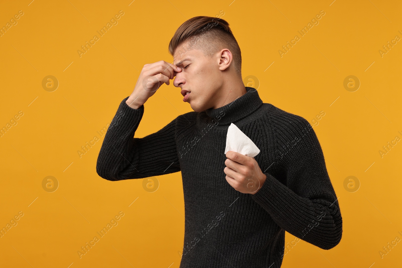 Photo of Sick man with tissue suffering from cold symptoms on orange background