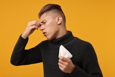 Photo of Sick man with tissue suffering from cold symptoms on orange background