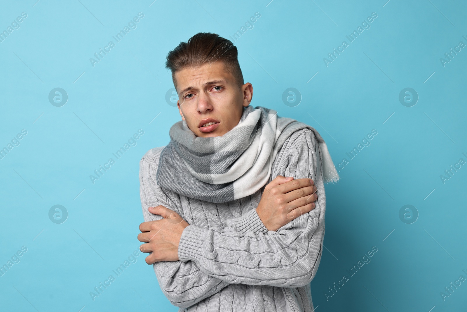 Photo of Sick man suffering from cold symptoms on light blue background