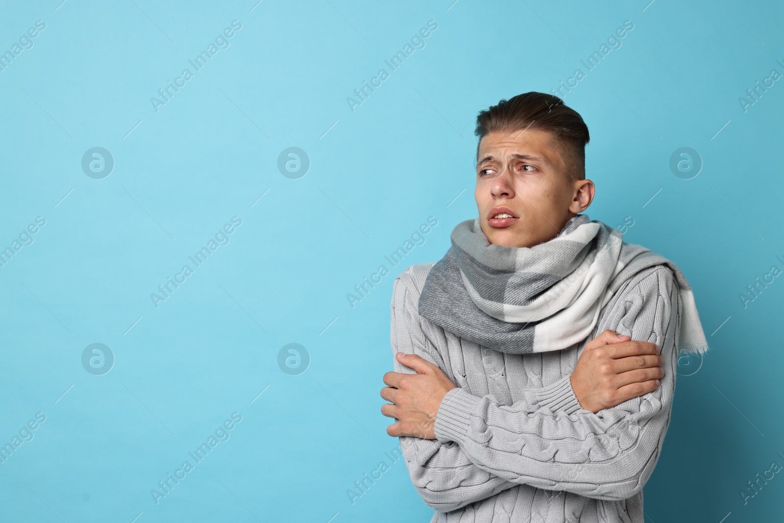 Photo of Sick man suffering from cold symptoms on light blue background, space for text