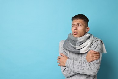 Photo of Sick man suffering from cold symptoms on light blue background, space for text