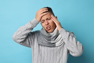 Photo of Sick man suffering from cold symptoms on light blue background