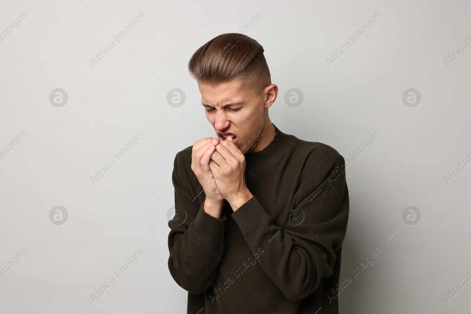 Photo of Sick man coughing on light grey background. Cold symptoms