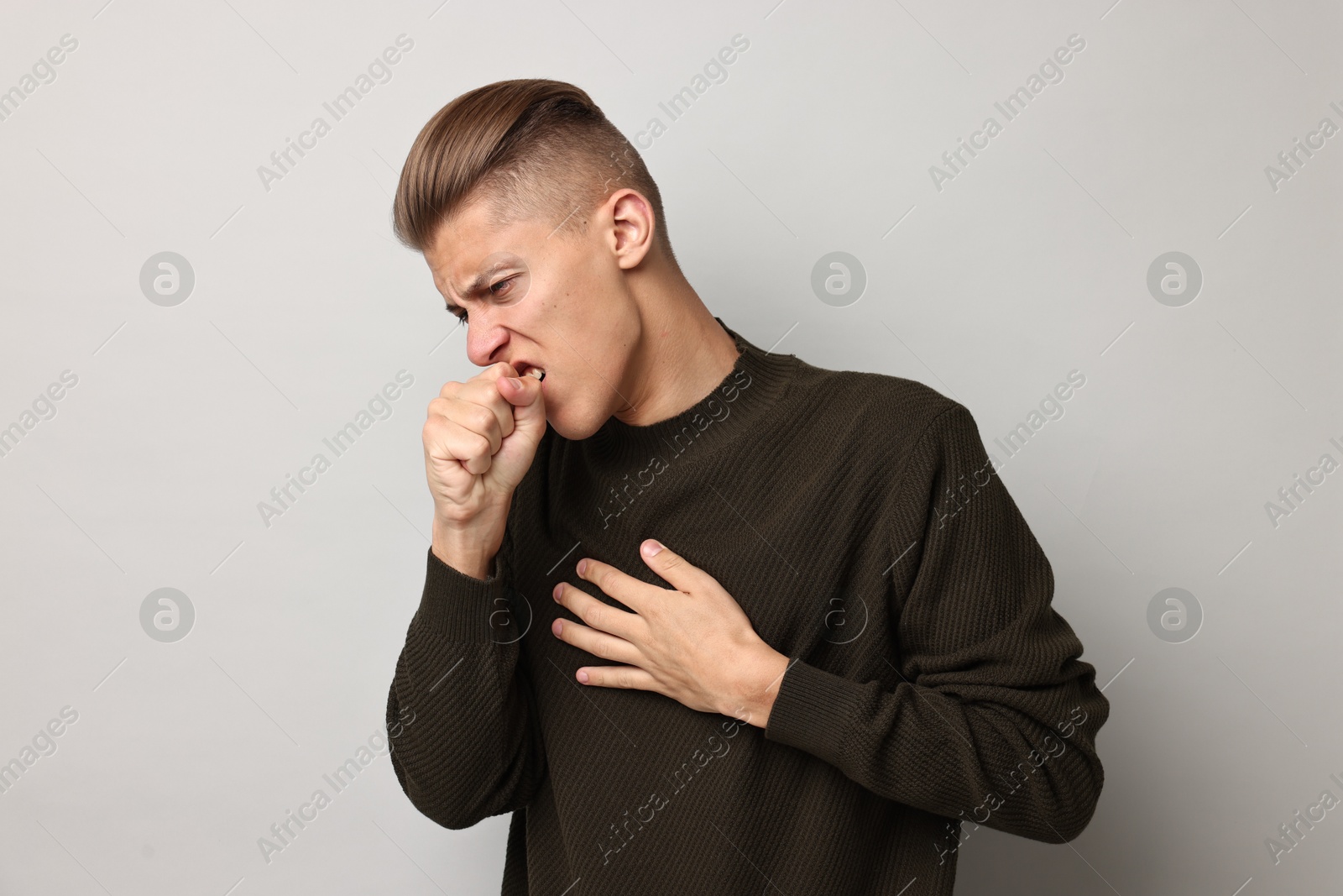 Photo of Sick man coughing on light grey background. Cold symptoms