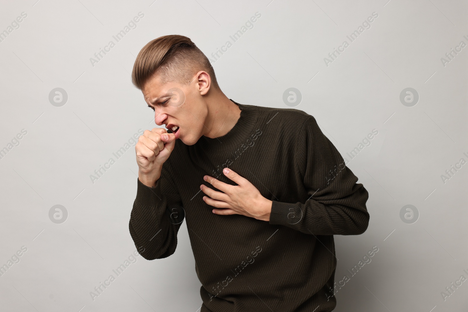 Photo of Sick man coughing on light grey background. Cold symptoms