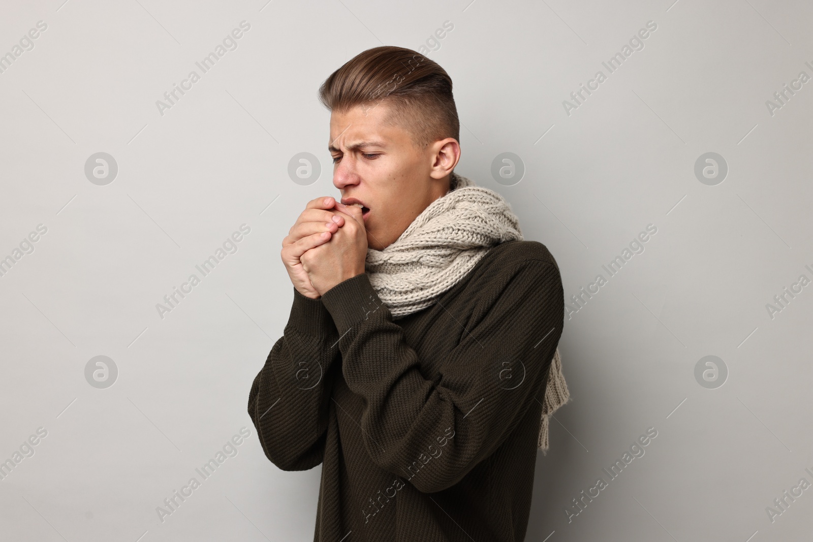 Photo of Sick man coughing on light grey background. Cold symptoms