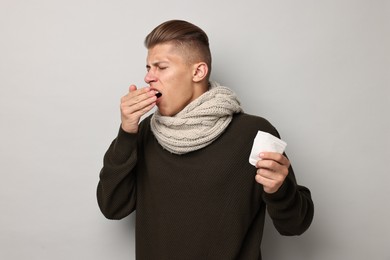 Photo of Sick man with tissue suffering from cold symptoms on light grey background
