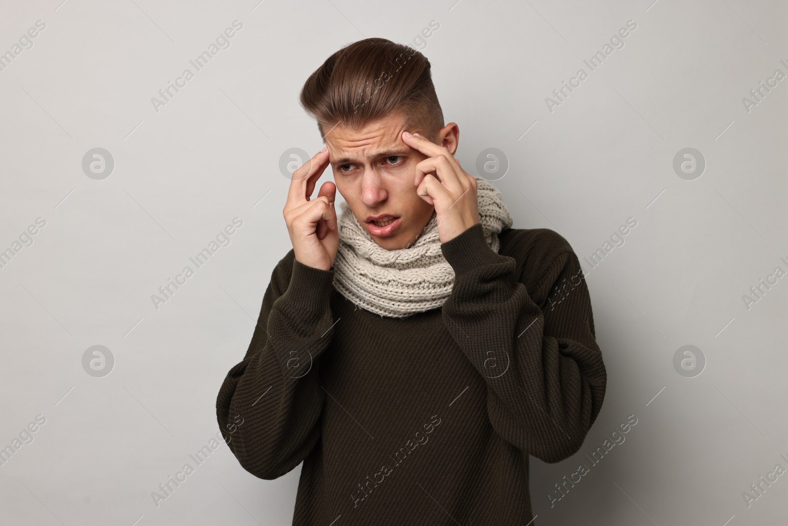 Photo of Sick man suffering from cold symptoms on light grey background