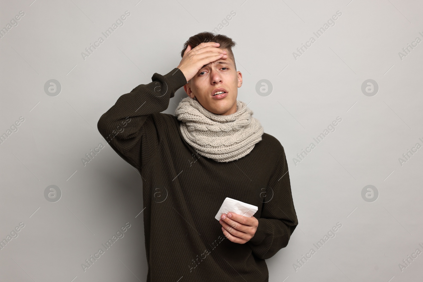 Photo of Sick man with tissue suffering from cold symptoms on light grey background