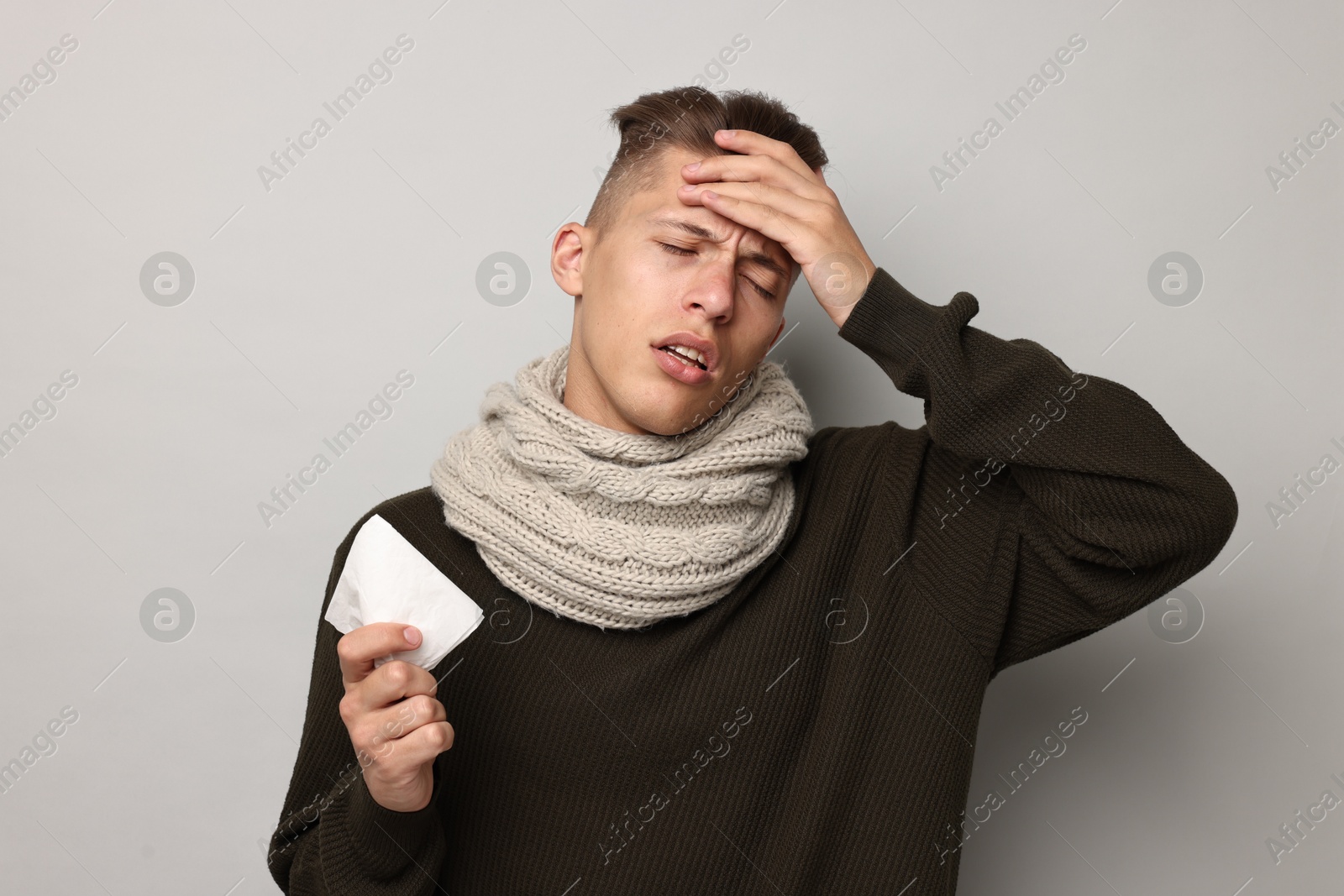 Photo of Sick man with tissue suffering from cold symptoms on light grey background