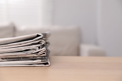 Stack of newspapers in different languages on table indoors. Space for text