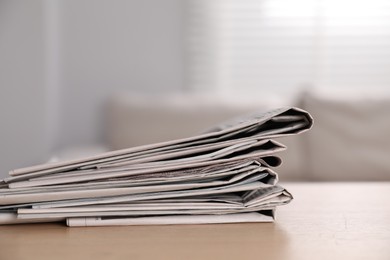 Stack of newspapers in different languages on table indoors